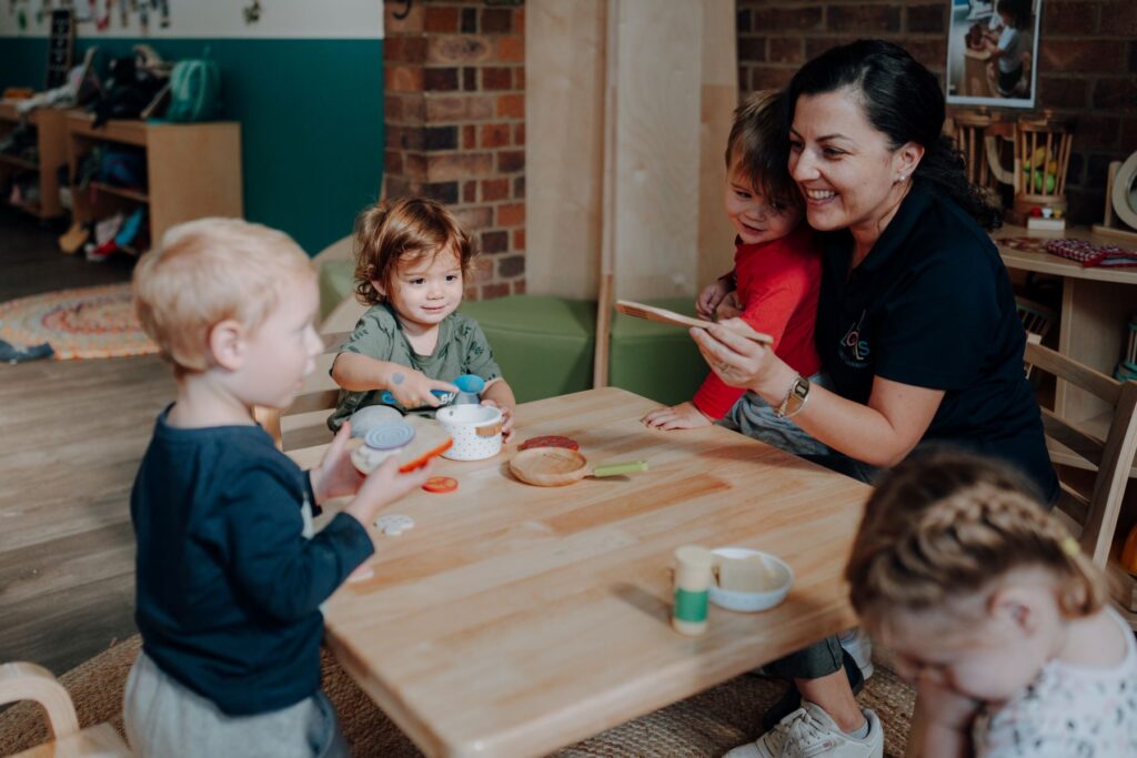 An early childhood educator sits at a table with children at Little Locals Early Learning, enjoing her childcare job at this Brisbane early learning centre.